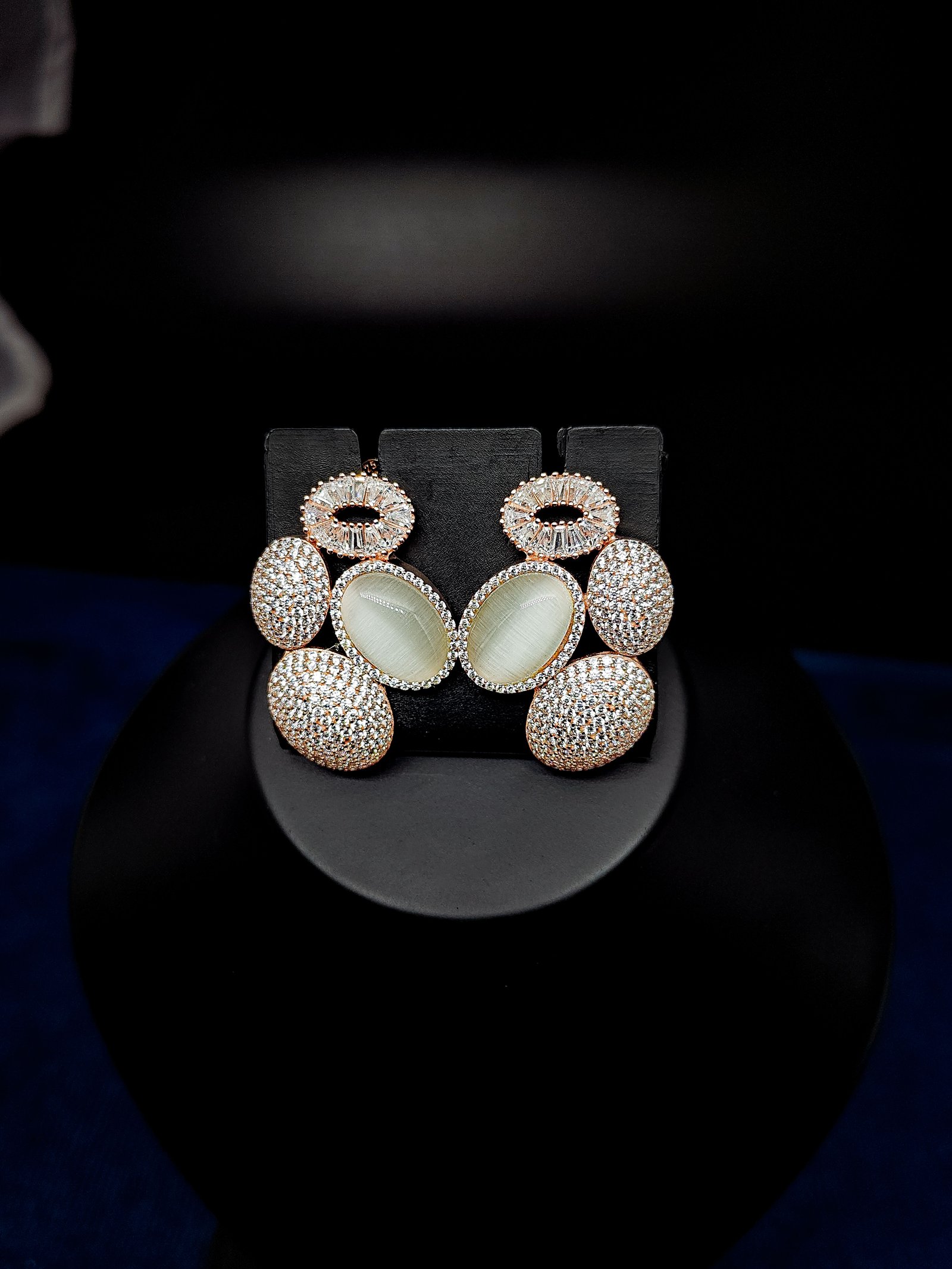 Rose gold-toned tiered drop earrings with a pale cabochon stone framed by pavé