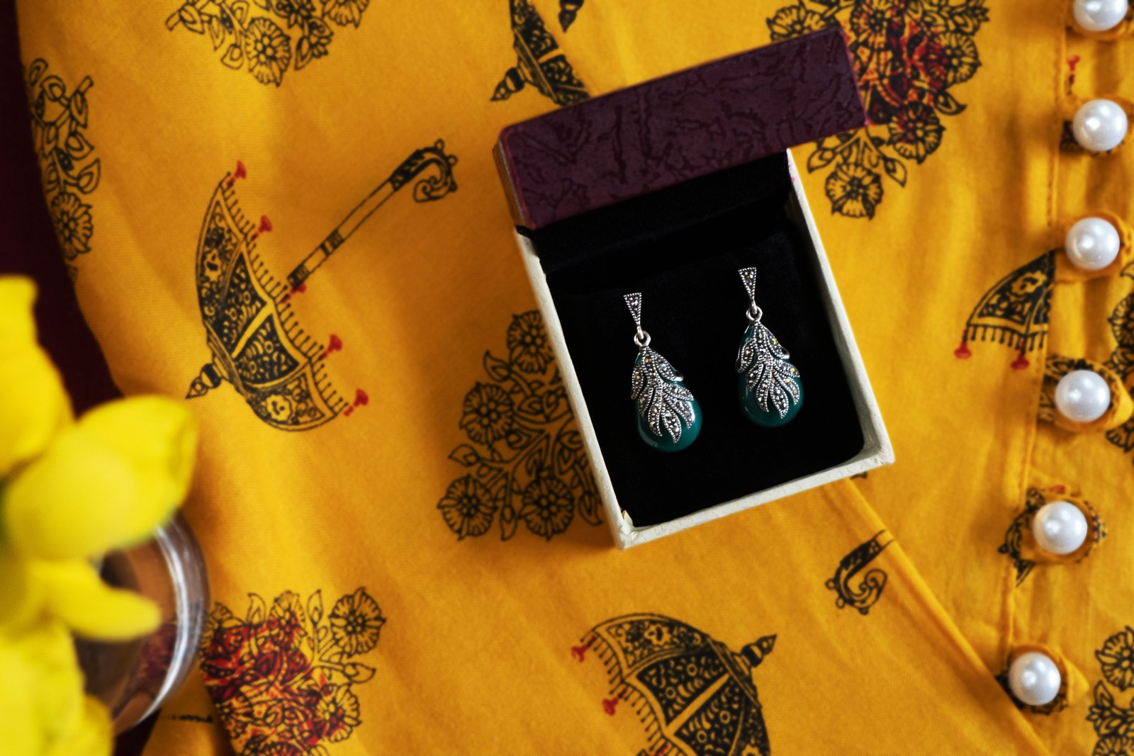 Silver-tone drop earrings with a teal teardrop stone in a leaf-patterned setting