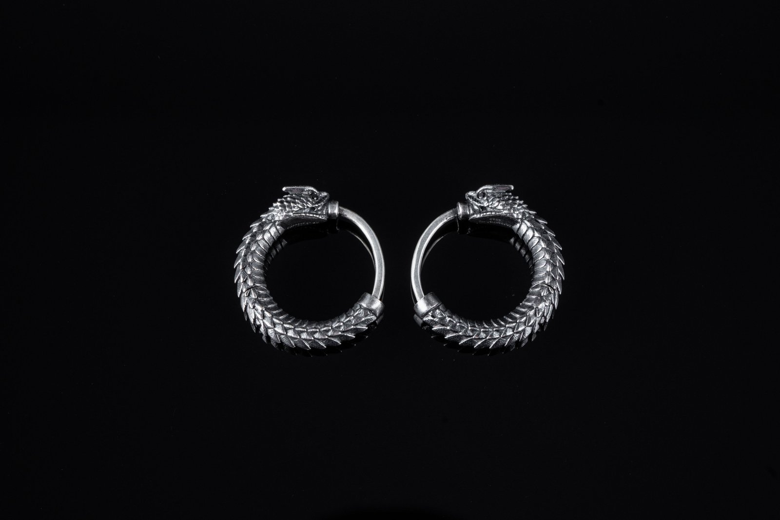 Oxidised silver-tone hoop earrings shaped like a scaled serpent