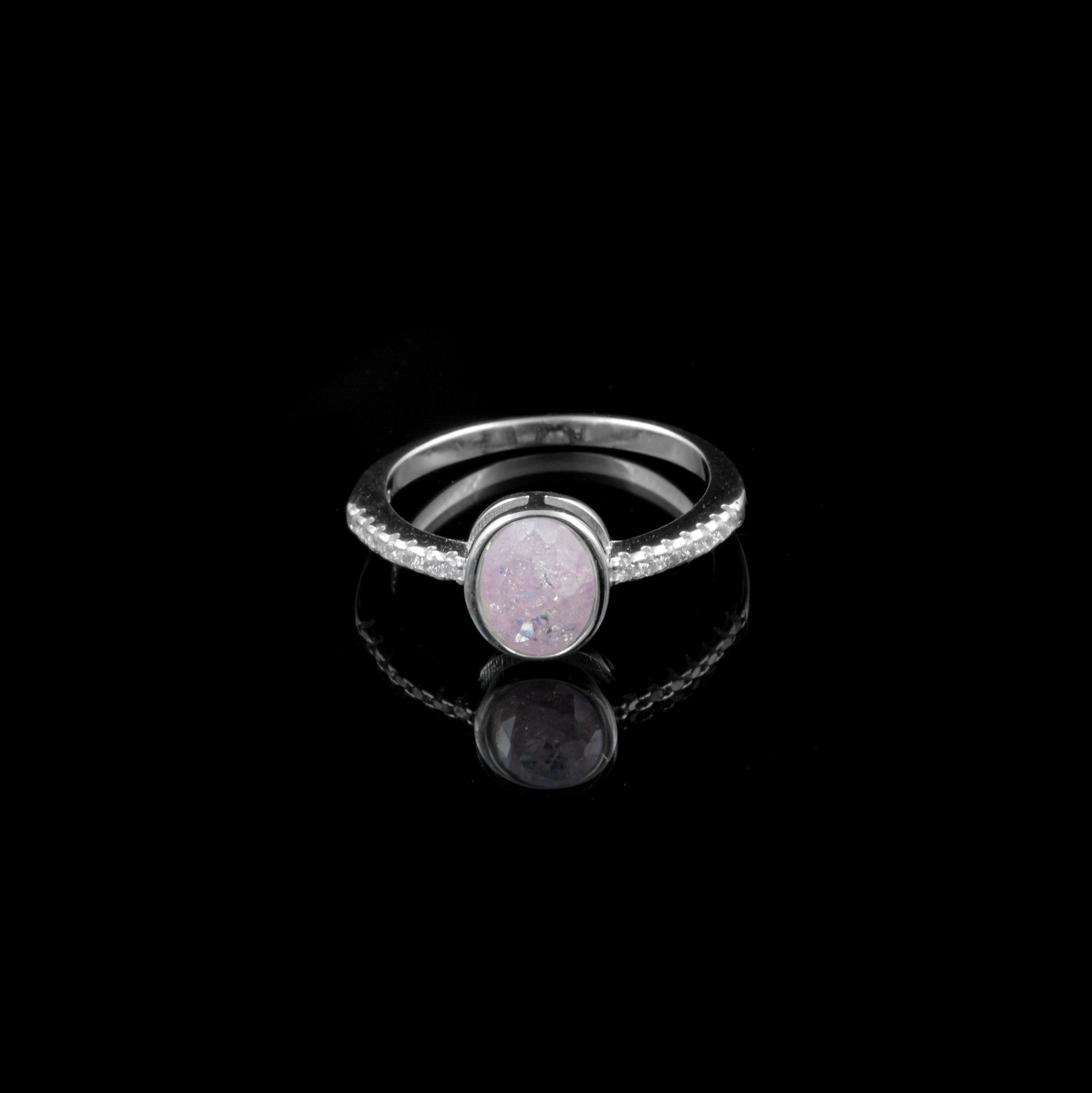 Ring with a round pale stone in a bezel setting on a pavé silver-tone band