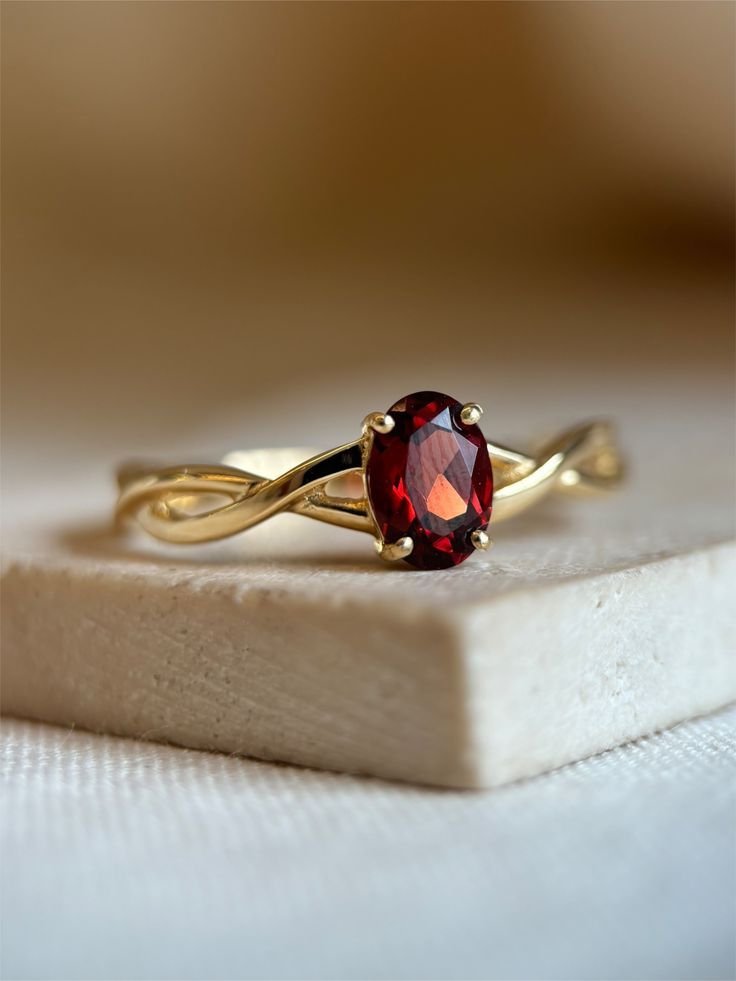 Ring with a red oval stone on a twisting gold-toned infinity band